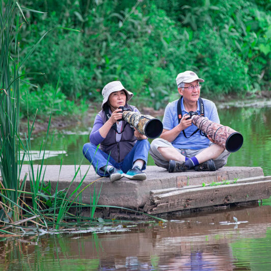 A couple sits on a doc photographing wildlife