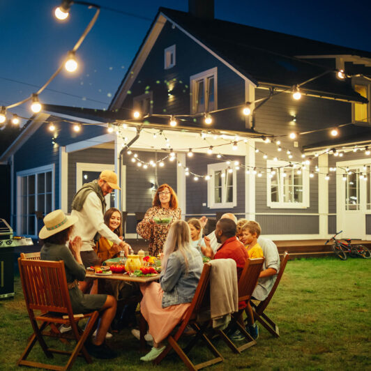 friends and family gather in residential backyard for dinner under the lights