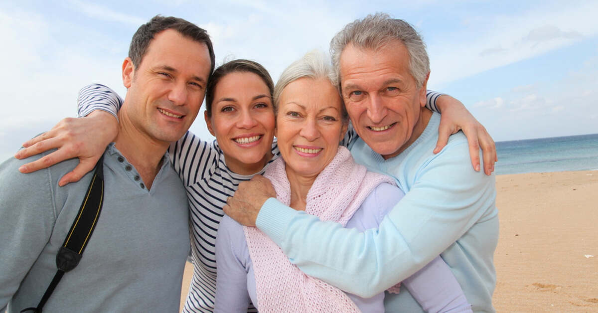a family hugs on the beach style=