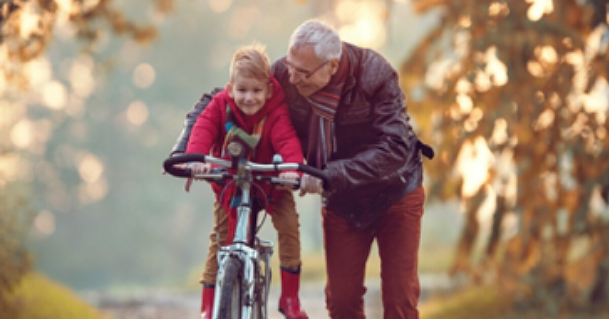 a grandfather helps a grandson ride a bike