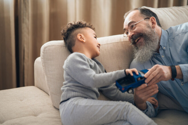 a grandpa sits on a couch with his grandson