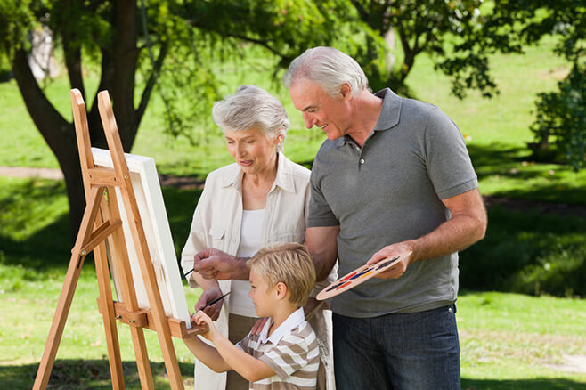 photo of grandparents painting outdoors with their grandson