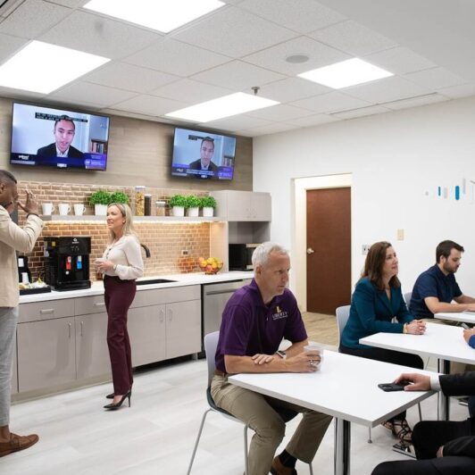 photo of office kitchen area with people sitting at tables talking with each other
