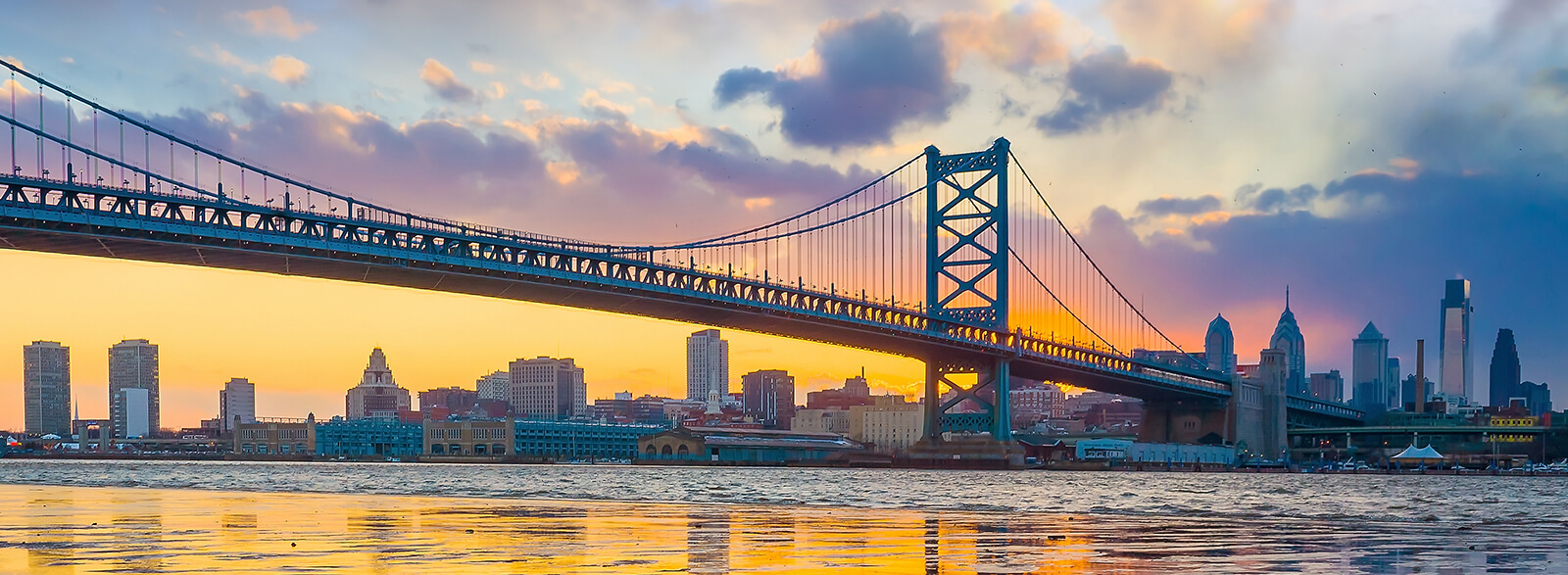 The Benjamin Franklin Bridge that connects Philadelphia, PA, and Camden, NJ, across the Delaware River at sunset with skyline in the background