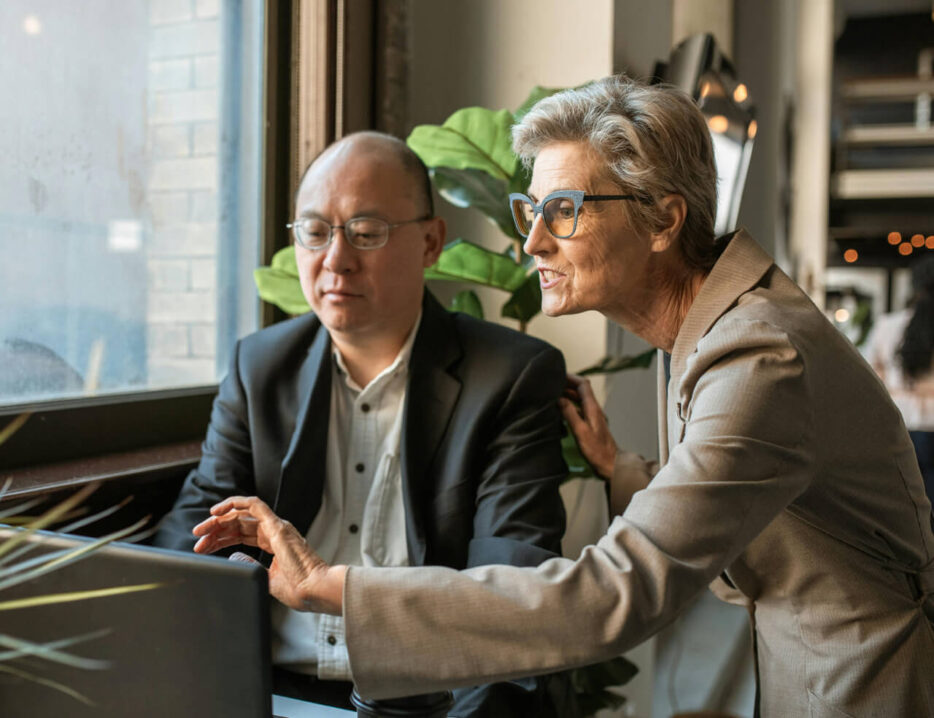 A couple who own a business review financials on a screen